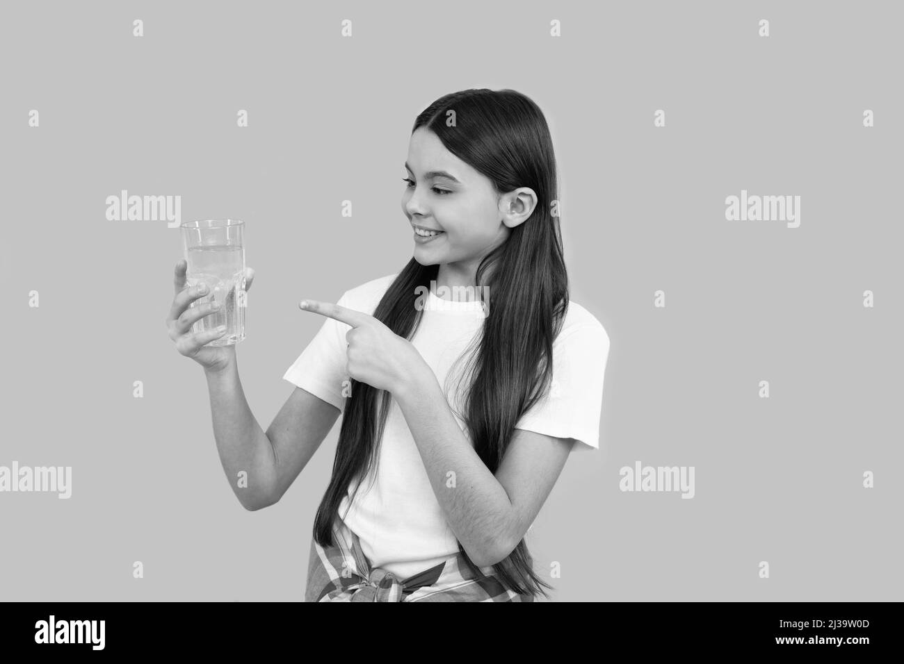 joyeux enfant pointant le doigt sur un verre d'eau pour maintenir l'équilibre quotidien de l'eau dans le corps, l'hydratation. Banque D'Images