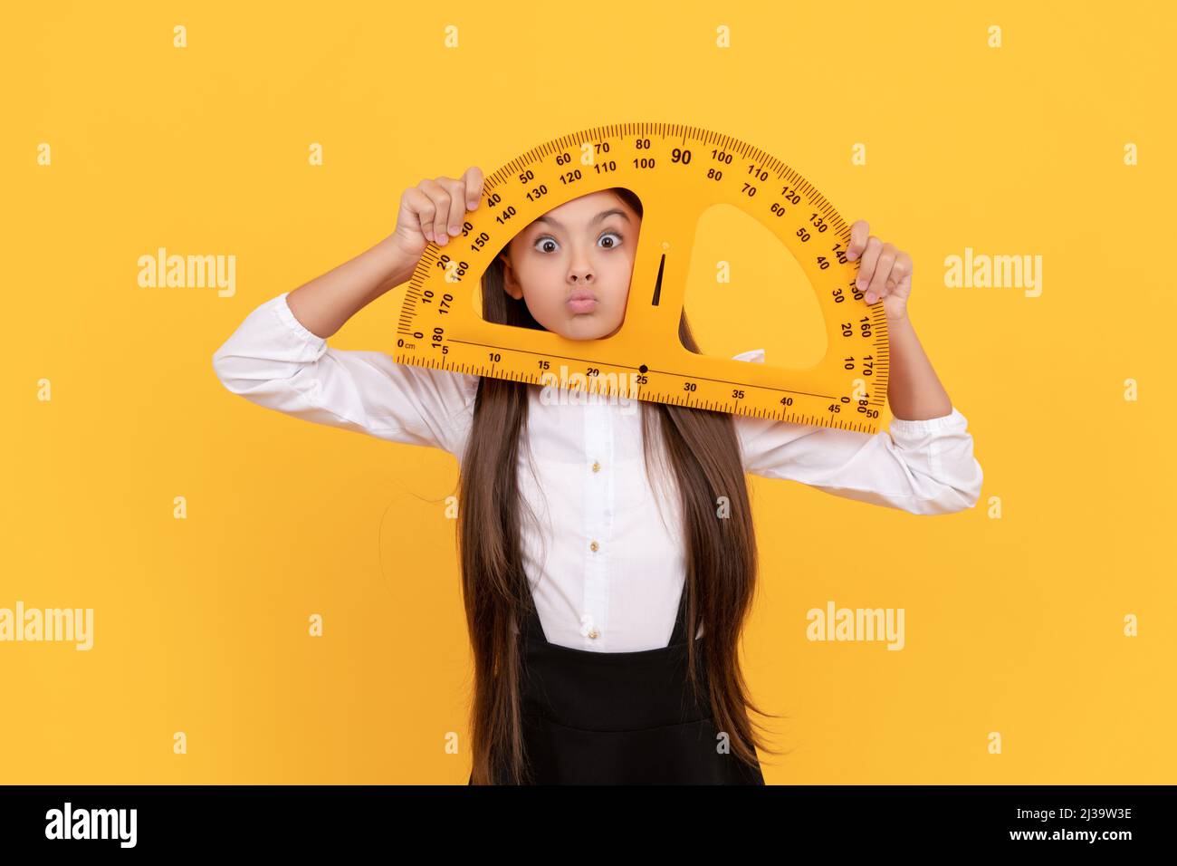 drôle de fille de l'adolescence dans l'uniforme d'école tiennent protracteur de mathématiques pour la mesure, logique Banque D'Images