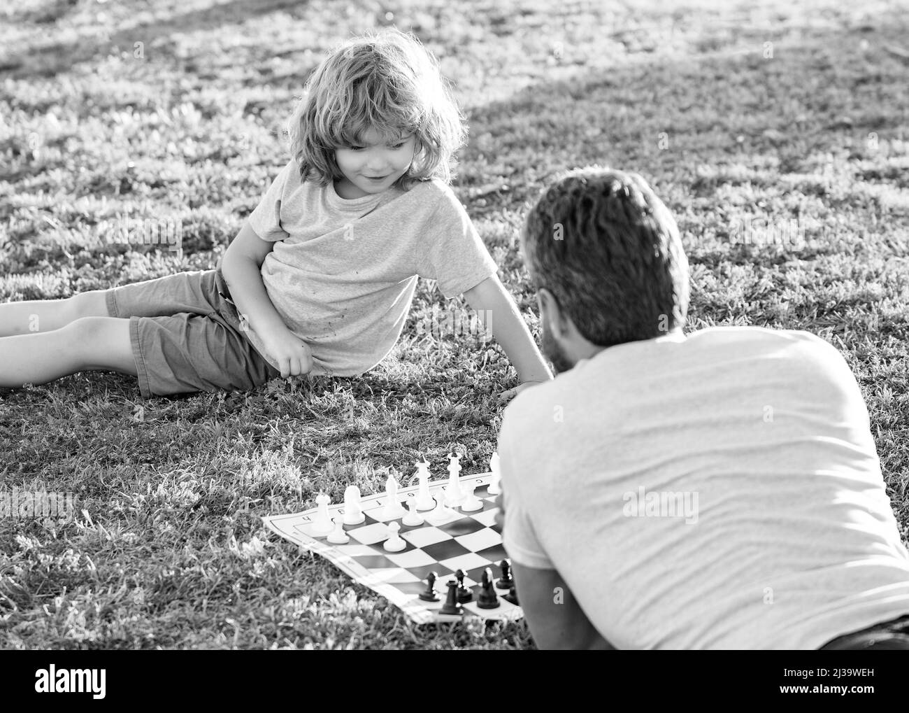 papa et gamin jouent au jeu logique. père et fils jouant aux échecs sur l'herbe. fête des pères. famille heureuse. Banque D'Images
