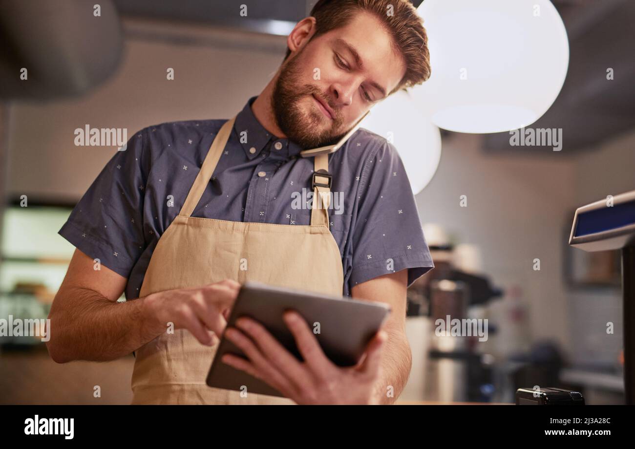 Assurez-vous que votre présence en ligne est tout ce qu'elle peut être. Photo d'un jeune homme utilisant une tablette numérique tout en travaillant dans un café. Banque D'Images