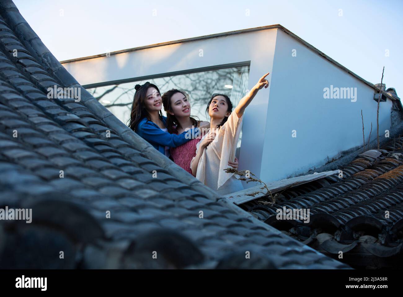 Jeunes femmes chinoises appréciant le paysage architectural traditionnel du siheyuan de Pékin à une fenêtre pleine hauteur - photo de stock Banque D'Images