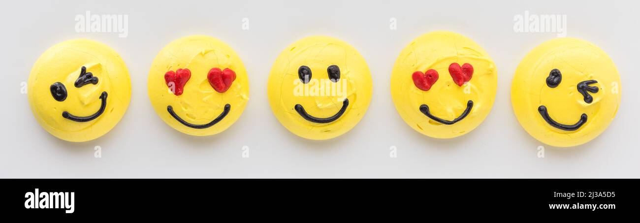 Une rangée de smiley visage emoji ou émoticone merengue cookies. Banque D'Images