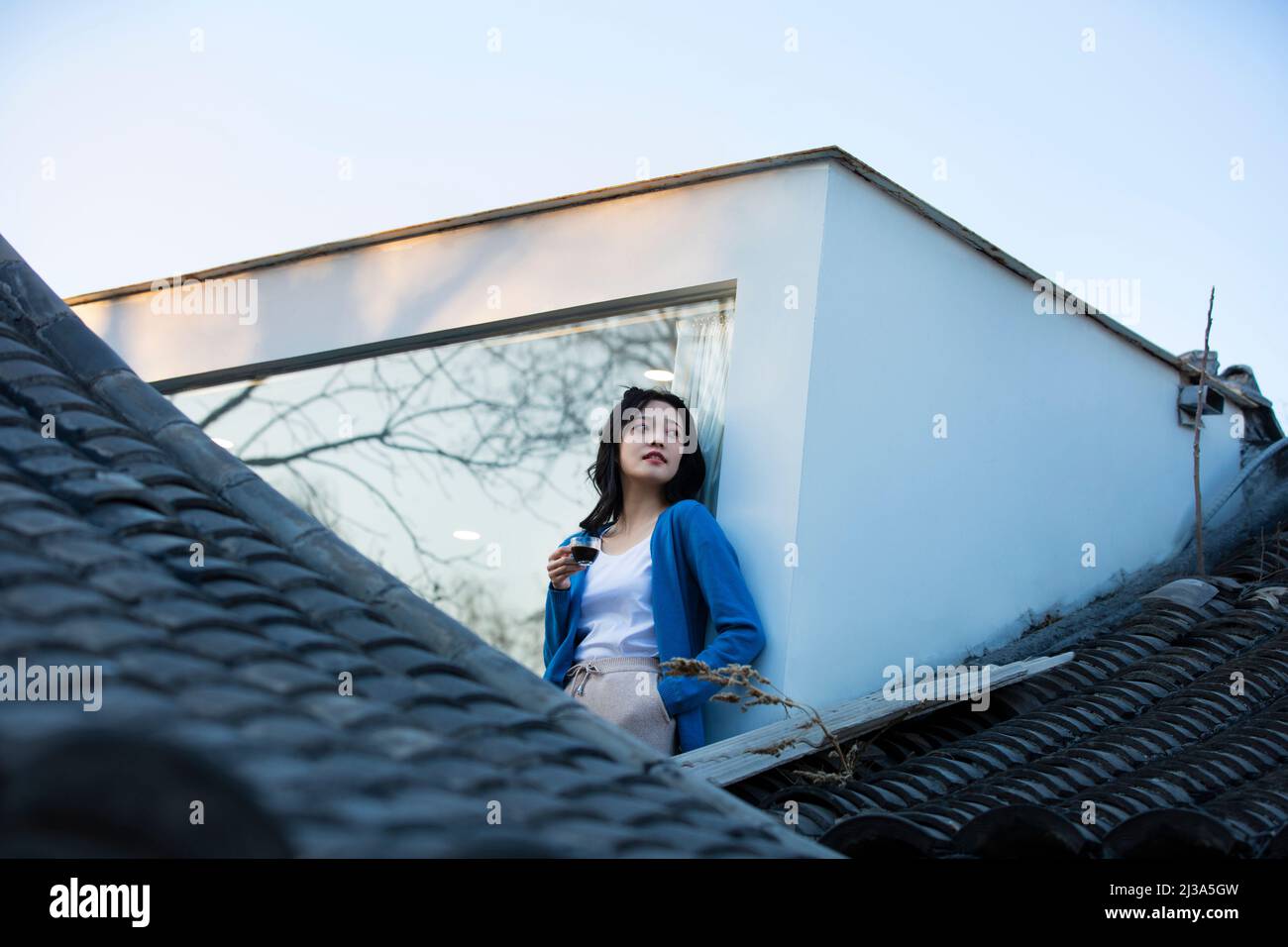 Jeune femme chinoise appréciant le paysage architectural traditionnel de siheyuan à Pékin à une fenêtre pleine hauteur - photo de stock Banque D'Images