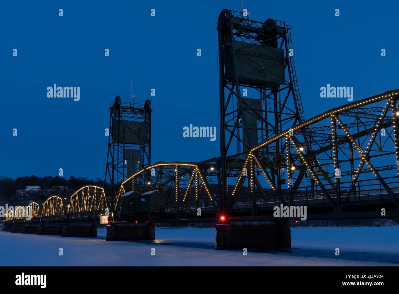 Le pont historique qui traverse la rivière Sainte Croix à Stillwater, Minnesota, vu au crépuscule en hiver avec des lumières de vacances. Banque D'Images