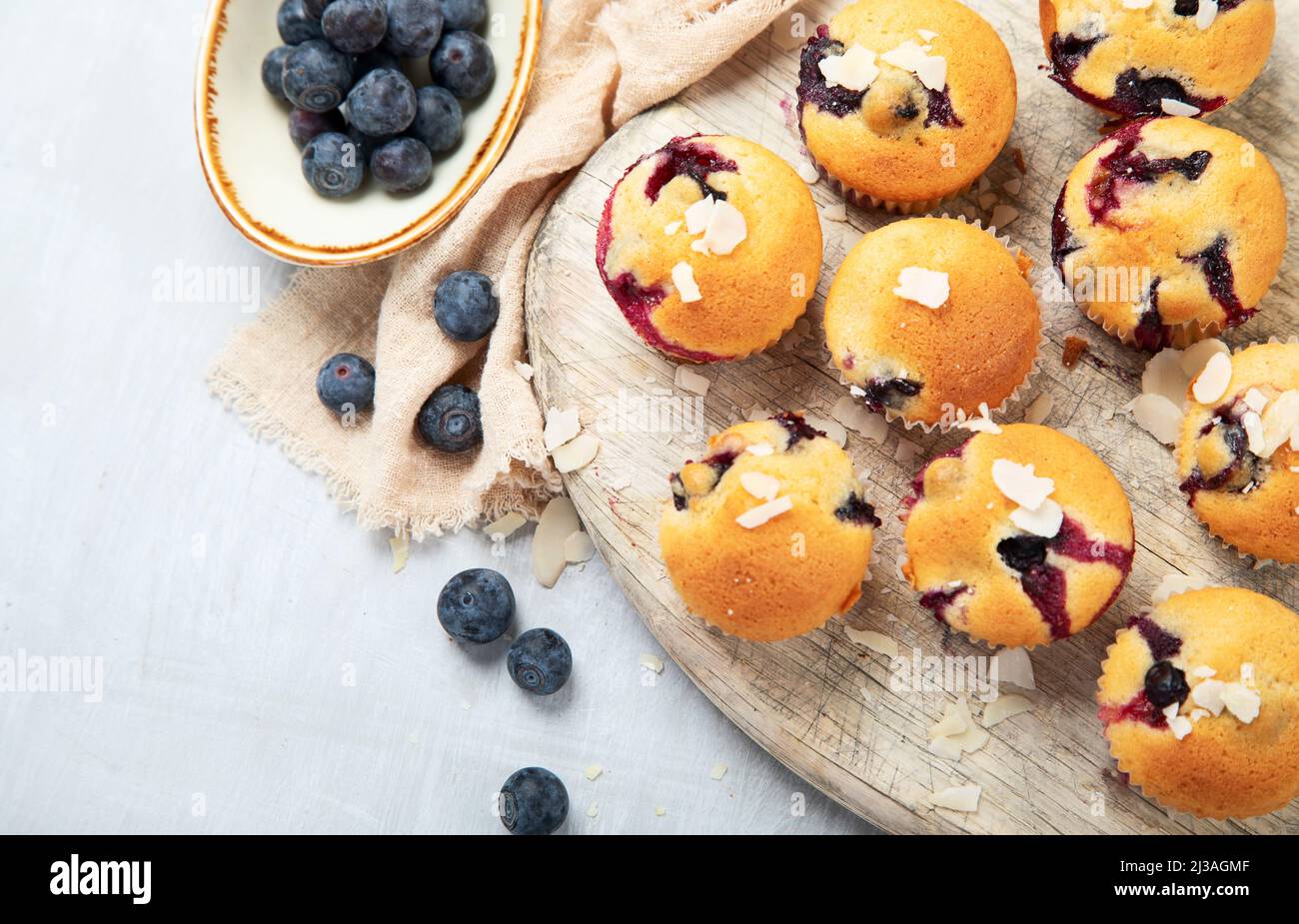 Muffin aux bleuets sur une assiette en bois. Baies fraîches et pâtisseries sucrées sur fond blanc, vue du dessus. Banque D'Images