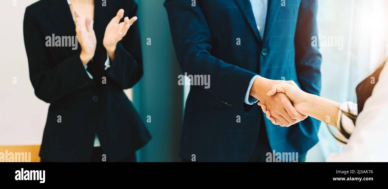 Une femme d'affaires applaudisse et se congrat pendant que deux gens d'affaires se secouent la main après avoir fait affaire ou accord. Travail et réussite concept. Banque D'Images