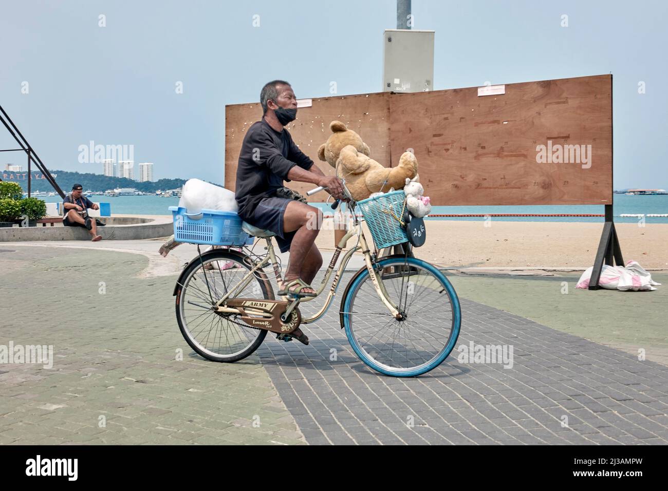 Homme à vélo avec un grand ours en peluche dans le panier Photo Stock -  Alamy