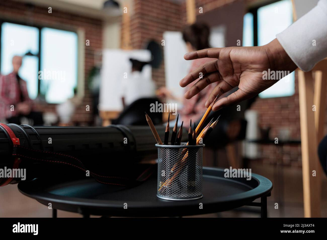 Gros plan sur les crayons graphiques pris main par les étudiants dans le studio de créativité. En arrière-plan équipe multi ethnique dessin vase esquisse sur toile blanche travaillant à la technique d'esquisse. Résolutions du nouvel an Banque D'Images