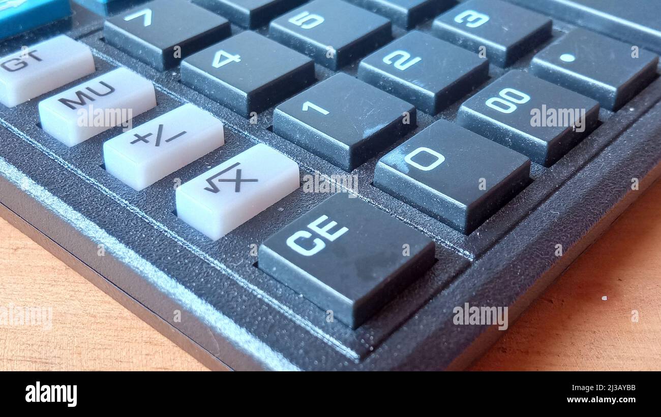 Vue en gros plan des boutons noirs de la calculatrice sur la table en bois Banque D'Images