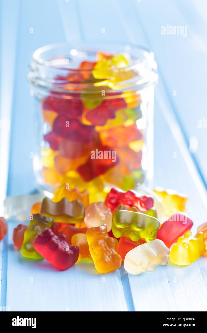 Bonbons à la gelée et à l'ours. Confiseries sucrées colorées sur table bleue. Banque D'Images