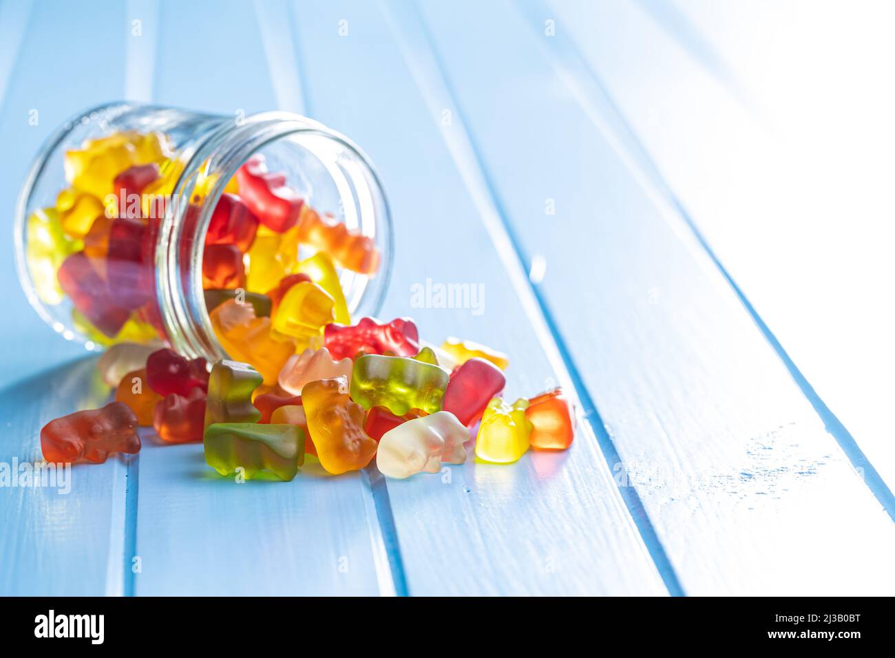 Bonbons à la gelée et à l'ours. Confiseries sucrées colorées sur table bleue. Banque D'Images