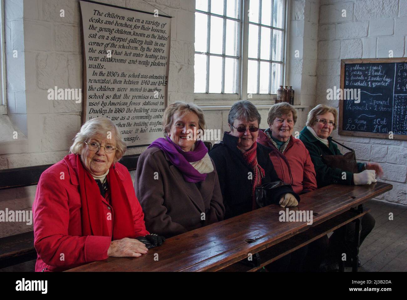 Groupe de femmes âgées, visiteurs au Black Country Living Museum, revivant leurs journées scolaires dans la salle de classe victorienne, Dudley, Royaume-Uni Banque D'Images