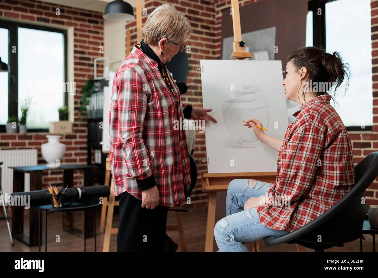 Professeur d'art principal montrant la technique graphique aux jeunes élèves pendant la leçon de créativité en studio scolaire. Peintre femme dessin vase esquisse à l'aide d'un crayon d'esquisse travaillant à la croissance personnelle Banque D'Images