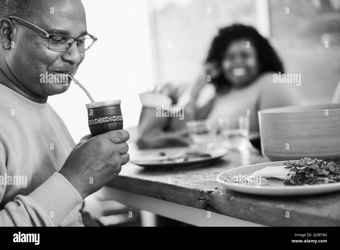 Heureux père noir buvant yerba mate pendant le déjeuner à la maison - foyer principal sur la tasse - montage noir et blanc Banque D'Images