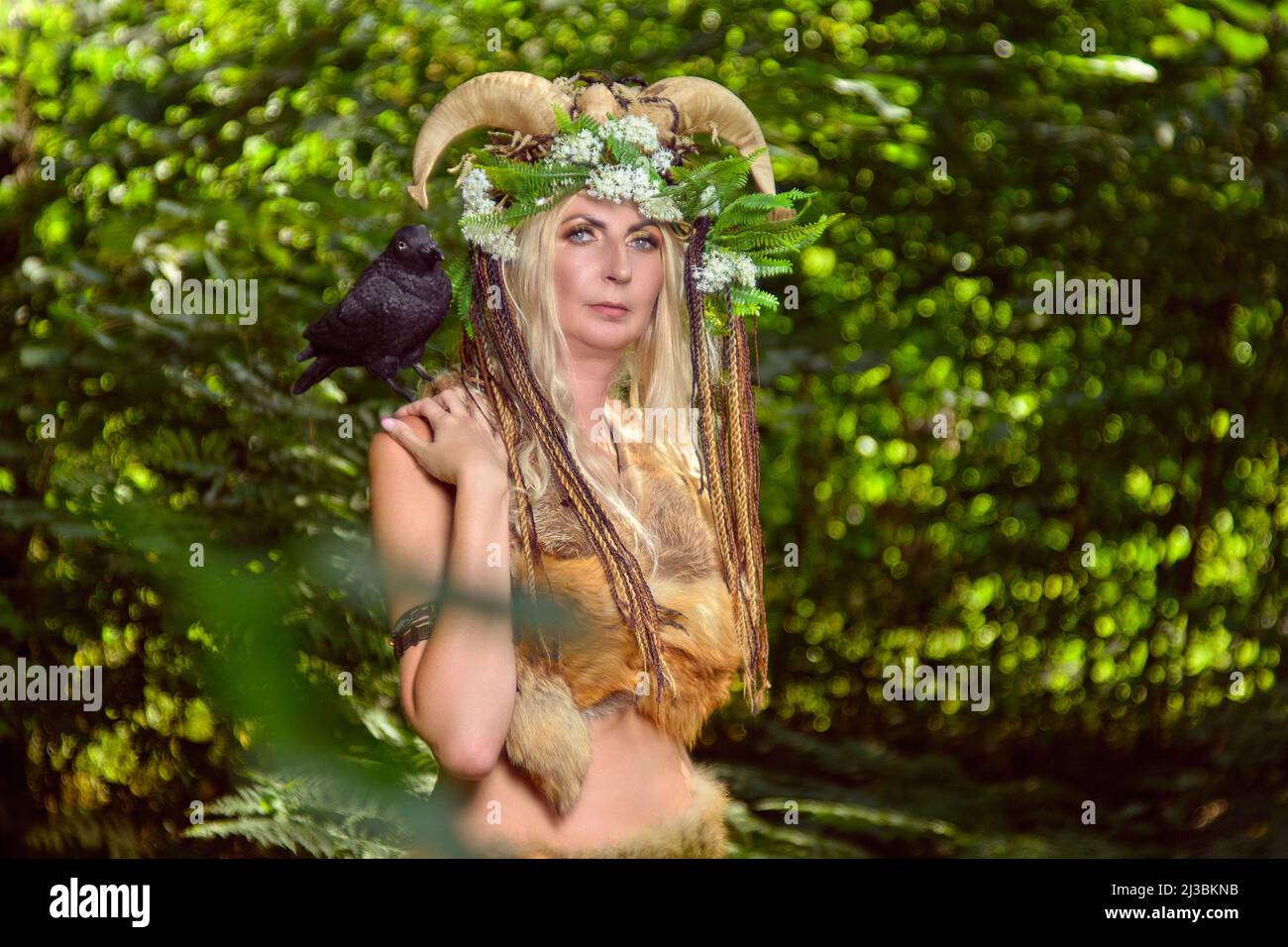 Femme dans la forêt vêtue de peaux et de fourrures. Sur la tête de la couronne des cornes. Concept fabuleux Banque D'Images