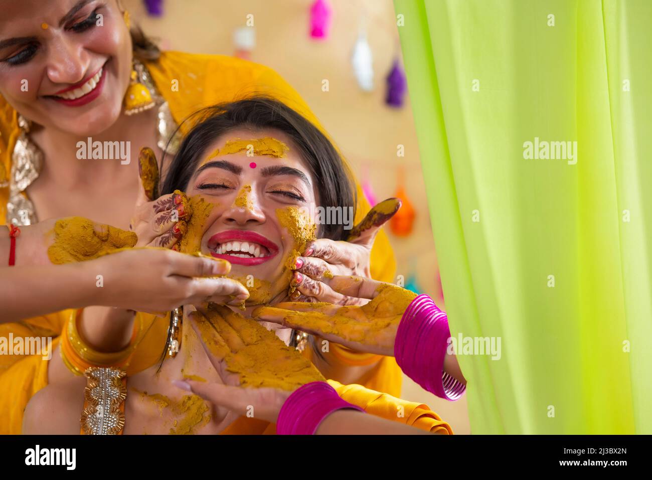 Mains de femmes appliquant de la pâte curcuma sur le visage de la mariée sur le rasam de haldi Banque D'Images