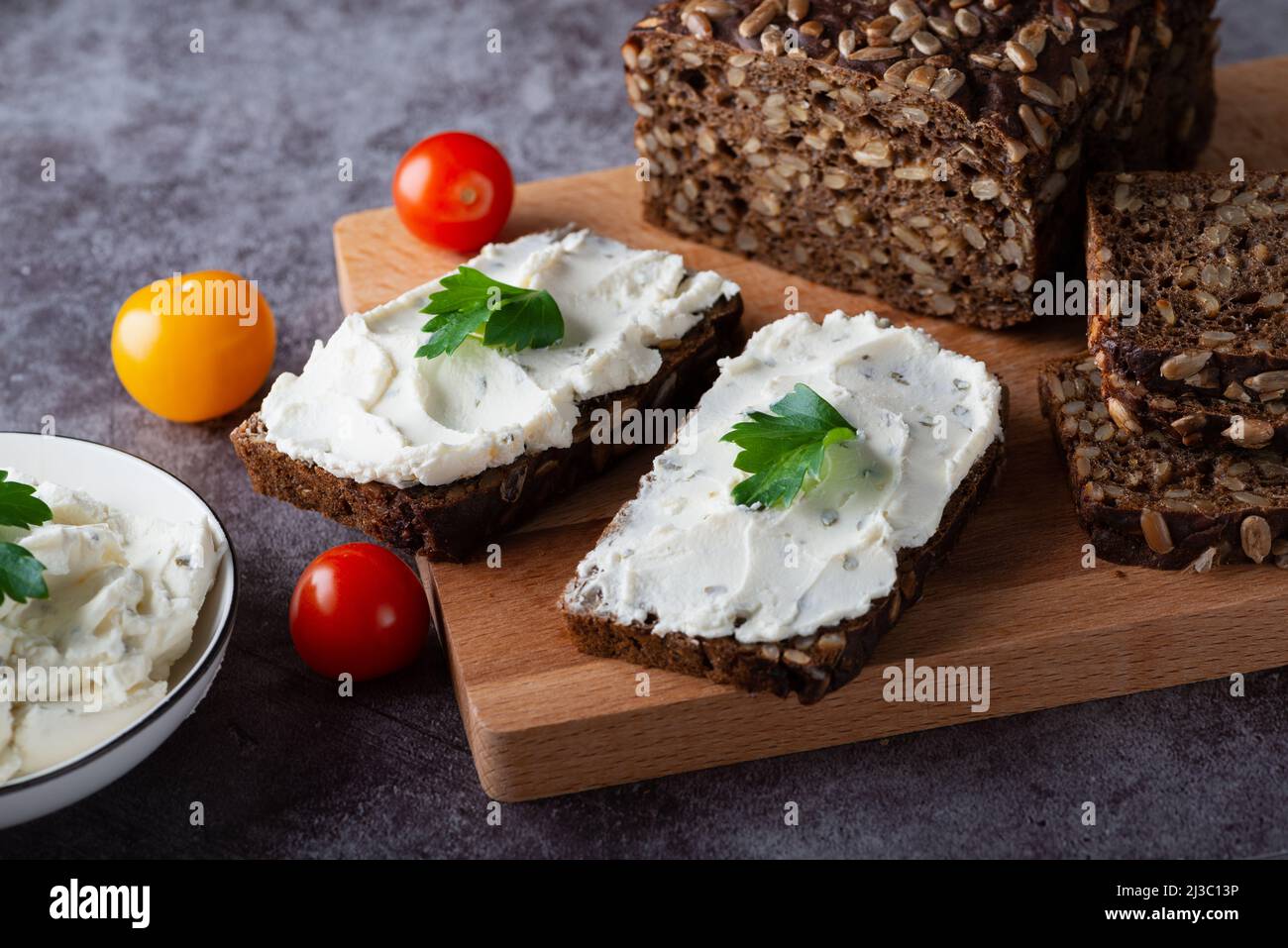 Pain de seigle avec fromage à la crème sur table grise. Pain de seigle de grain entier avec graines Banque D'Images