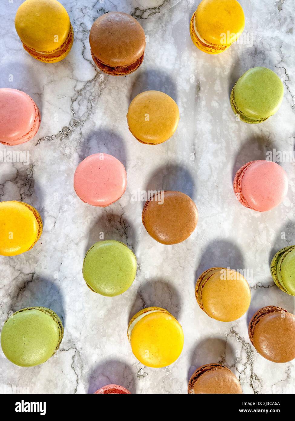 Macarons français colorés sur fond de marbre blanc vu d'en haut. Banque D'Images