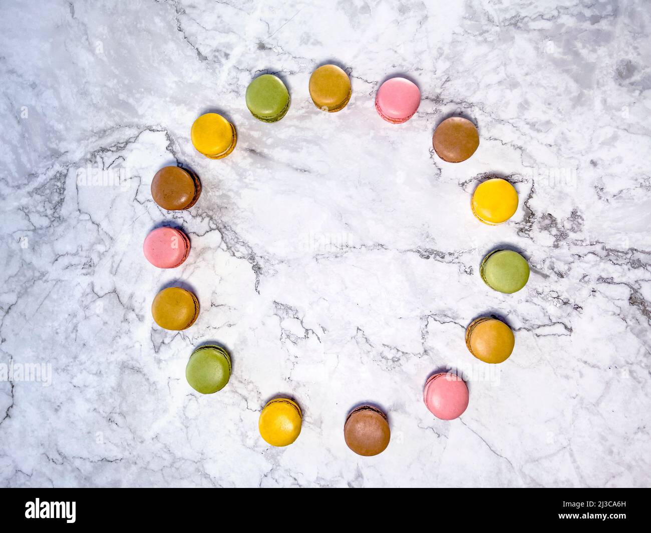 Macarons français colorés sur fond de marbre blanc vu d'en haut. Banque D'Images