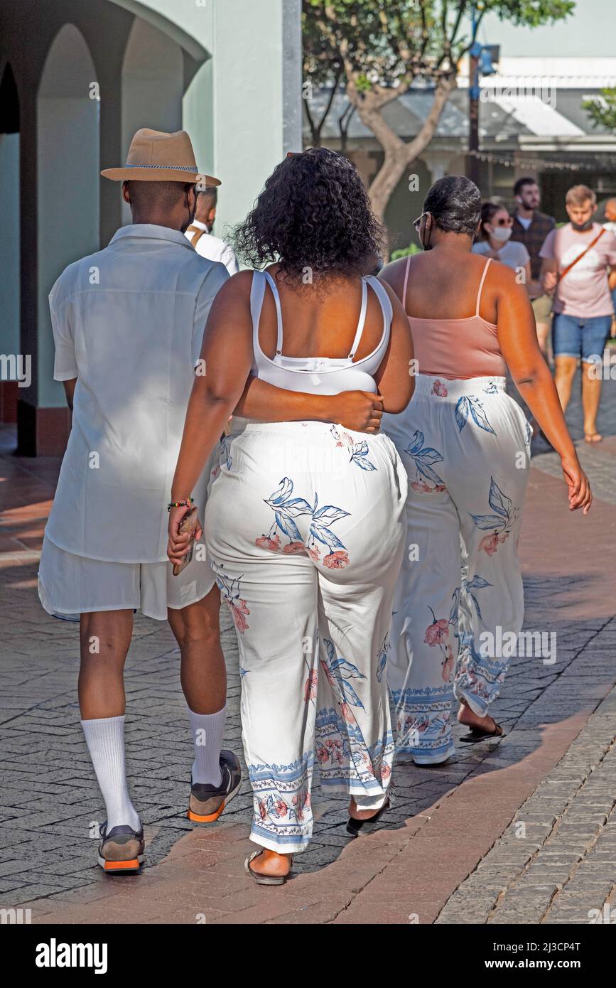 Le Cap, Afrique du Sud. 2022. Vue arrière de deux dames et un homme mince marchant sur le front de mer à Cape Town. Banque D'Images