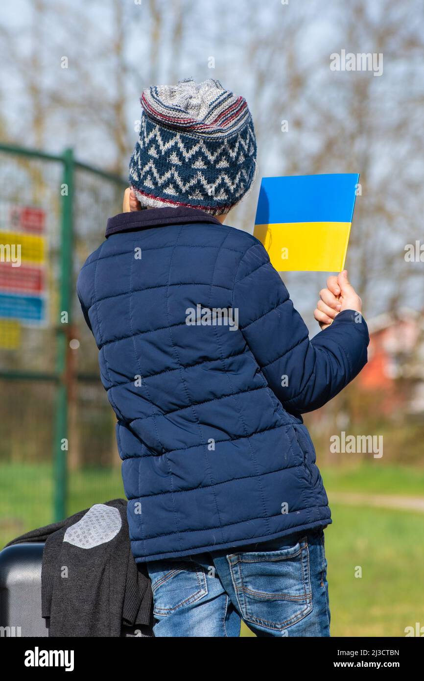 Enfant ou enfant avec vêtements d'hiver, chapeau et drapeau ukrainien, le profil de l'enfant est sur le drapeau. La guerre en Ukraine, causée par Poutine et la Russie, réfugié Banque D'Images