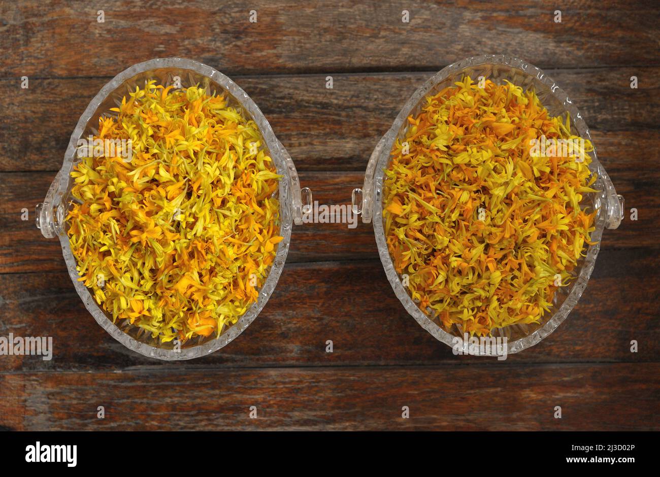 Pétales de marigold jaune, Tagetes, infusion de plantes, tisanes, Pétale de marigold presque sèche pour faire de la tisane dans un bol en verre sur la table en bois. Banque D'Images