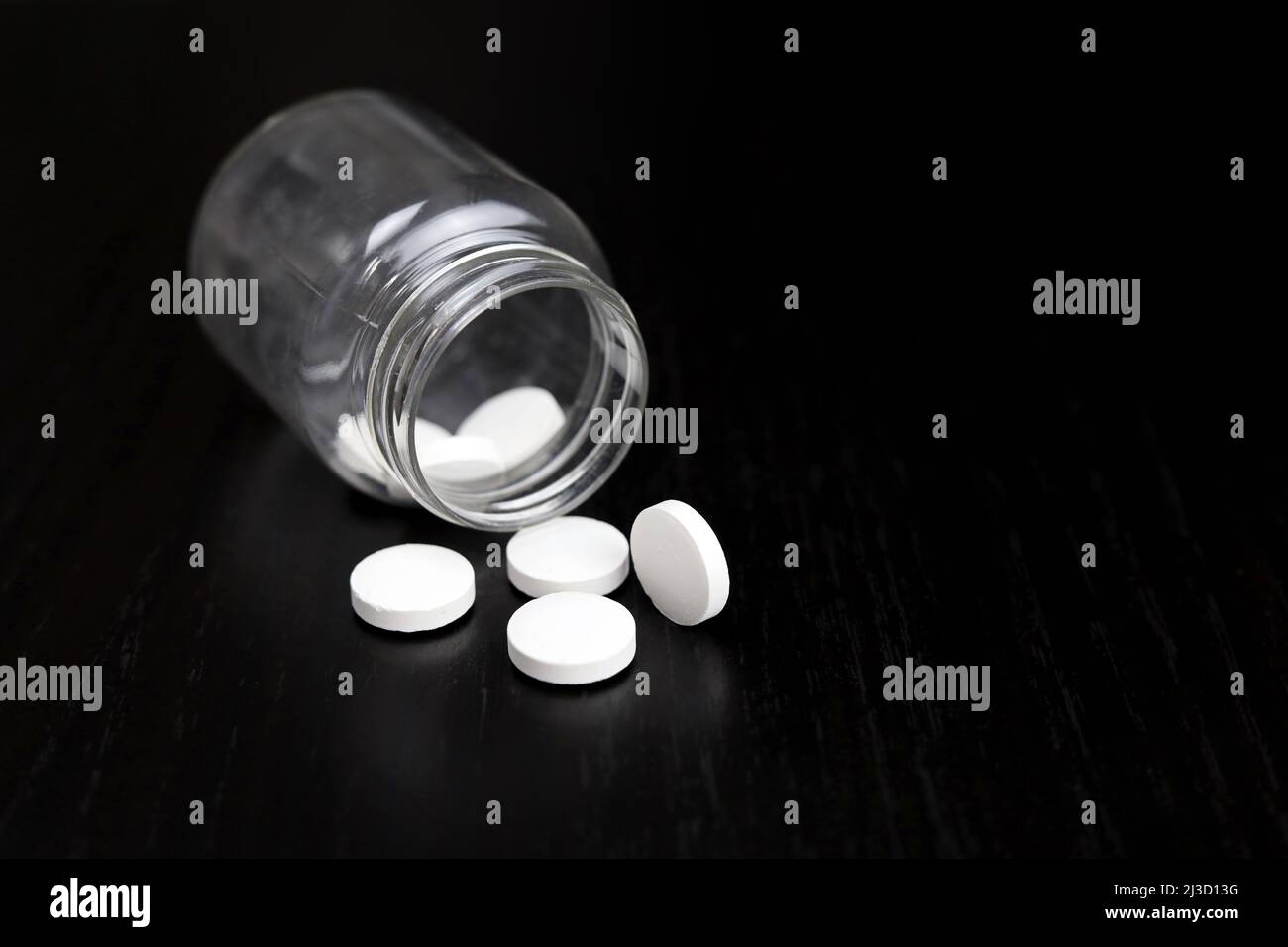 Pilules blanches sur une table en bois sombre, médicaments dispersés d'une bouteille. Pharmacie, antibiotiques ou vitamines Banque D'Images