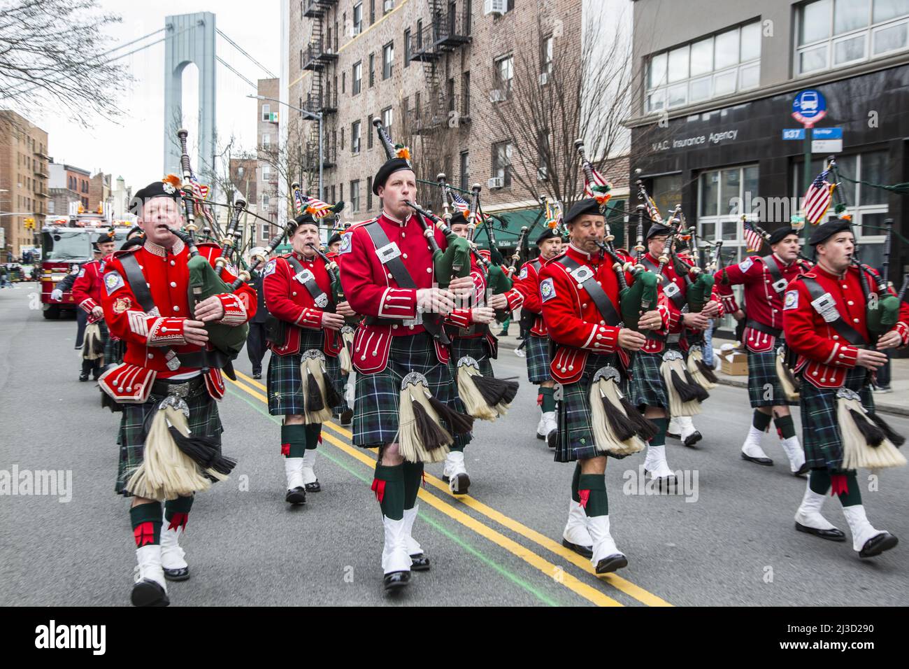 New York Fire Department Emerald Society Pipe Band marche dans Bay Ridge, Brooklyn Saint Patrick's Day Parade à Brooklyn, NY. La tour du pont Verrazano se distingue en arrière-plan. Banque D'Images