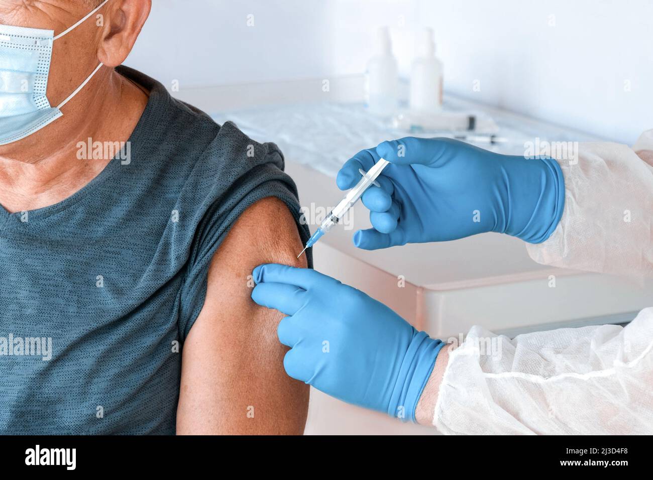 Médecin vaccinant l'homme supérieur en clinique. Vaccination des personnes âgées. Médecin donnant COVID19 injection de vaccin coronavirus au masque de l'ancien homme Banque D'Images