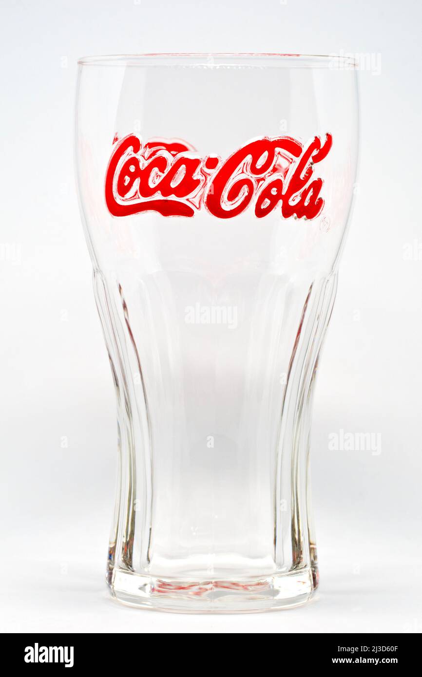 Gros plan sur la forme distinctive et reconnaissable d'un verre à boissons gazeuses de marque Coca Cola vide, avec la signature de la marque déposée en rouge. Banque D'Images