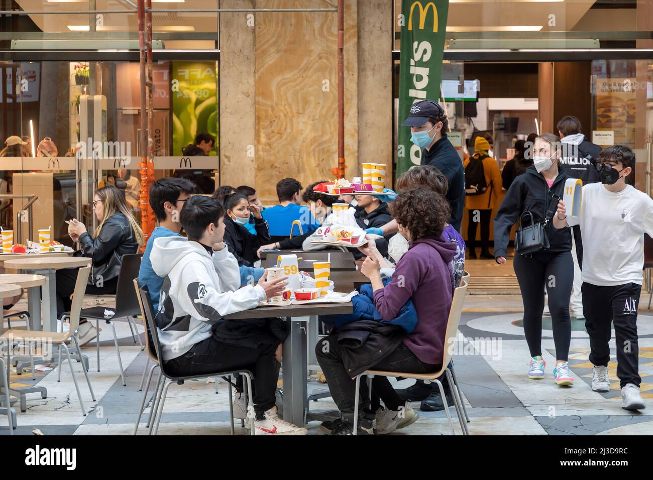 Naples, Italie - le 25 mars 2022 : groupe de jeunes adolescents assis à une table McDonald's en train de manger de la nourriture dans des paquets de papier. Banque D'Images