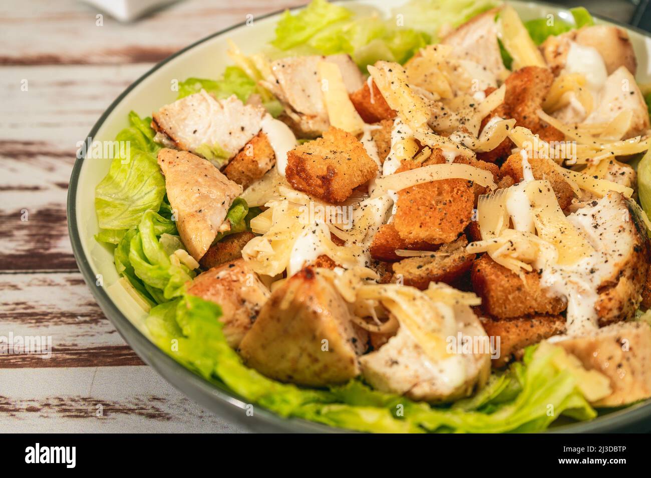 Salade César exquise avec de petites bouchées de poulet et une sauce aioli traditionnelle dans un petit bol sur une table rustique. Vue en hauteur. Gros plan. Gourme Banque D'Images