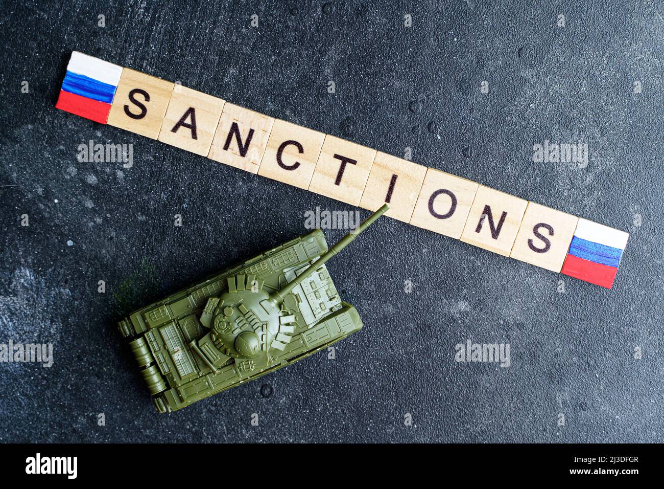 Concept de sanctions contre la Russie. Réservoir à jouets et inscription sanctions sur fond sombre. Conflit de guerre en Ukraine, défaut de paiement, crise économique et monétaire en Russie. Photo de haute qualité Banque D'Images