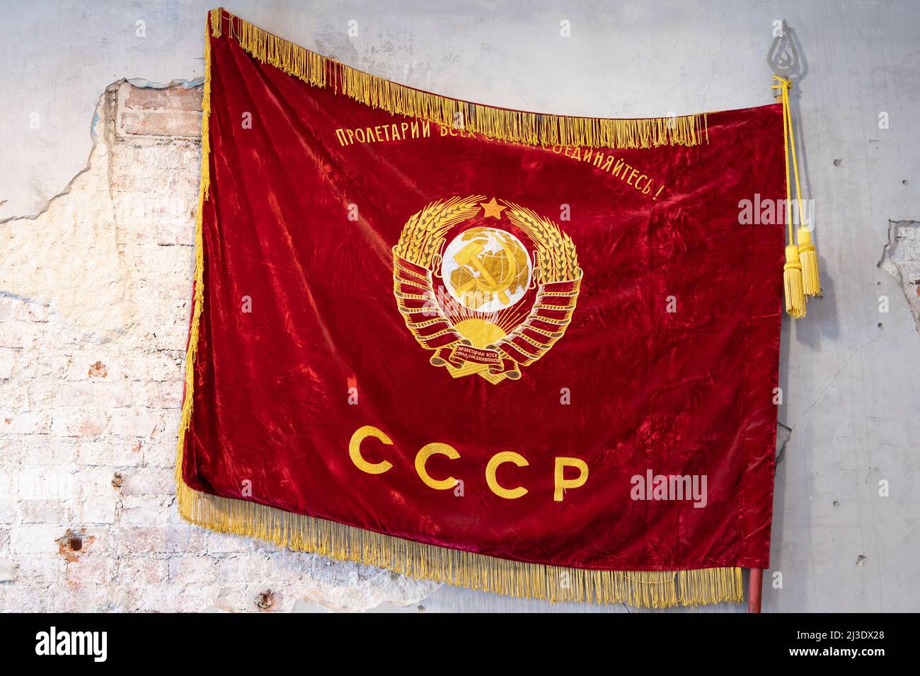 Drapeau rouge vintage de l'Union soviétique avec des armoiries d'or est sur un mur de grungy Banque D'Images