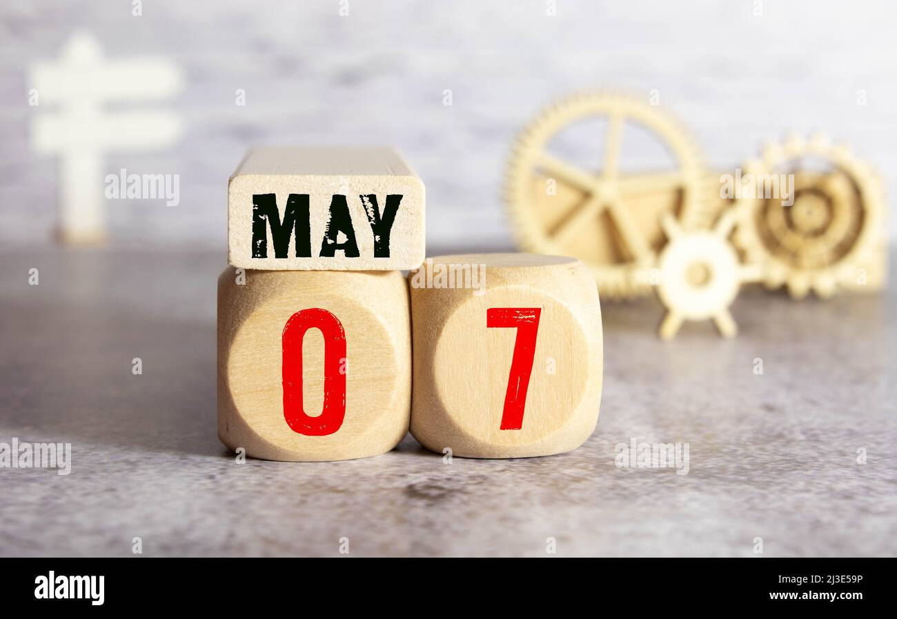 Mai 7, cube de calendrier en bois sur tissu de feutre jaune avec fleur de pivoine pour fond d'icône de date Banque D'Images