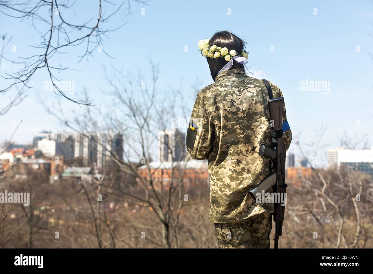 Une jeune femme en uniforme de camouflage militaire porte une mitraillette et une couronne de roses avec le paysage de la ville en arrière-plan. Membres de la Défense territoriale de Kiev, Anastasiia Mokhina, 24 ans, et Viacheslav Hohlyuk, 43 ans, Marié aujourd'hui sous les lois de la loi martiale à Kiev, Ukraine. (Photo de Mykhaylo Palinchak / SOPA Images/Sipa USA) Banque D'Images