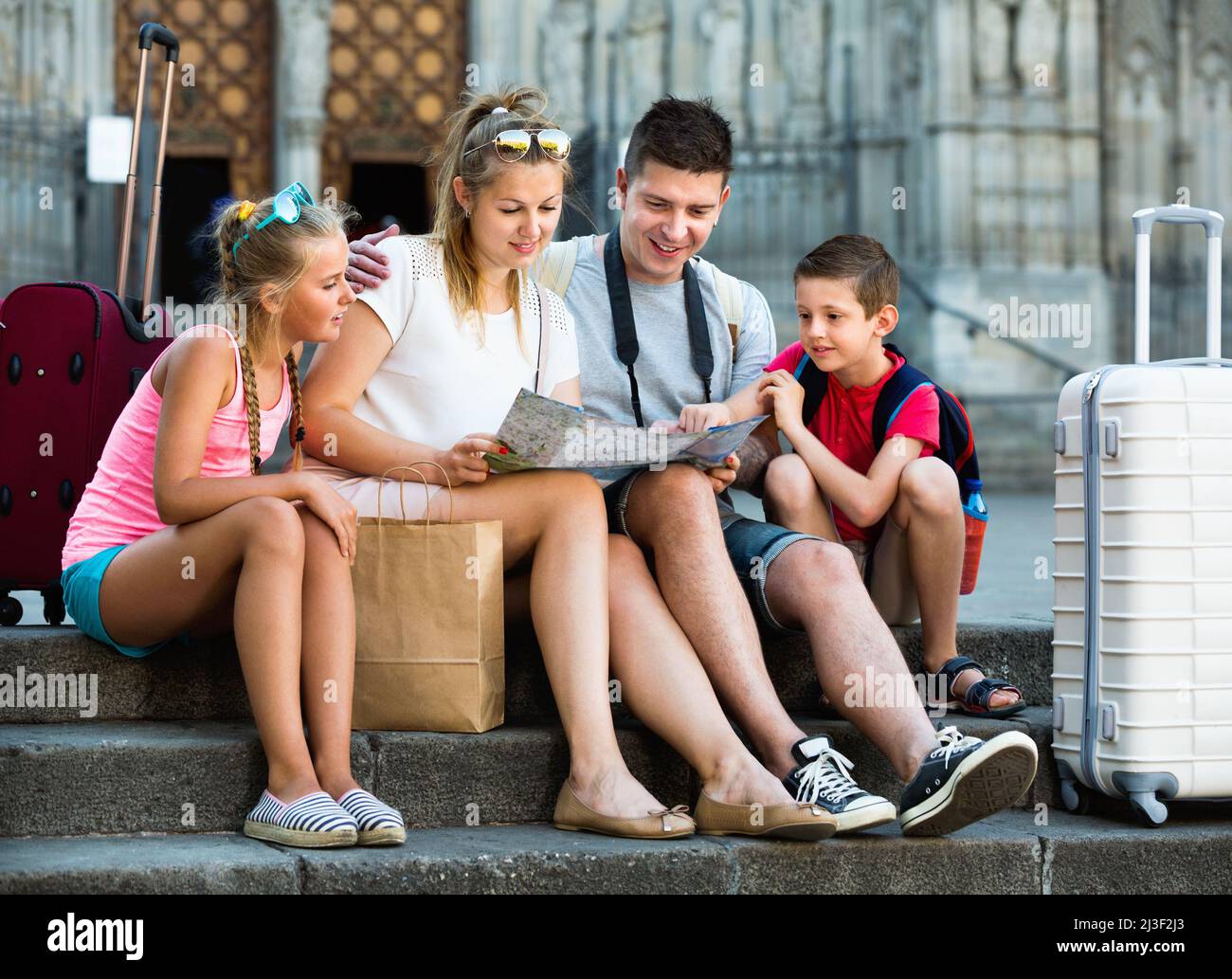 Famille de quatre personnes se détendant sur les marches de la vieille cathédrale et regardant la carte Banque D'Images