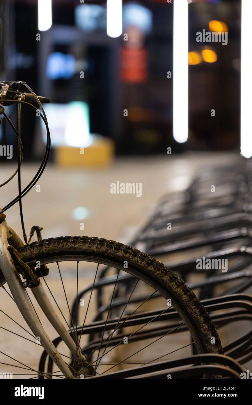 Vieux vélo de montagne sale utilisé pour les déplacements garés dans le rack de vélo au centre-ville. Photo prise le soir, lumière médiocre venant de la rue Banque D'Images
