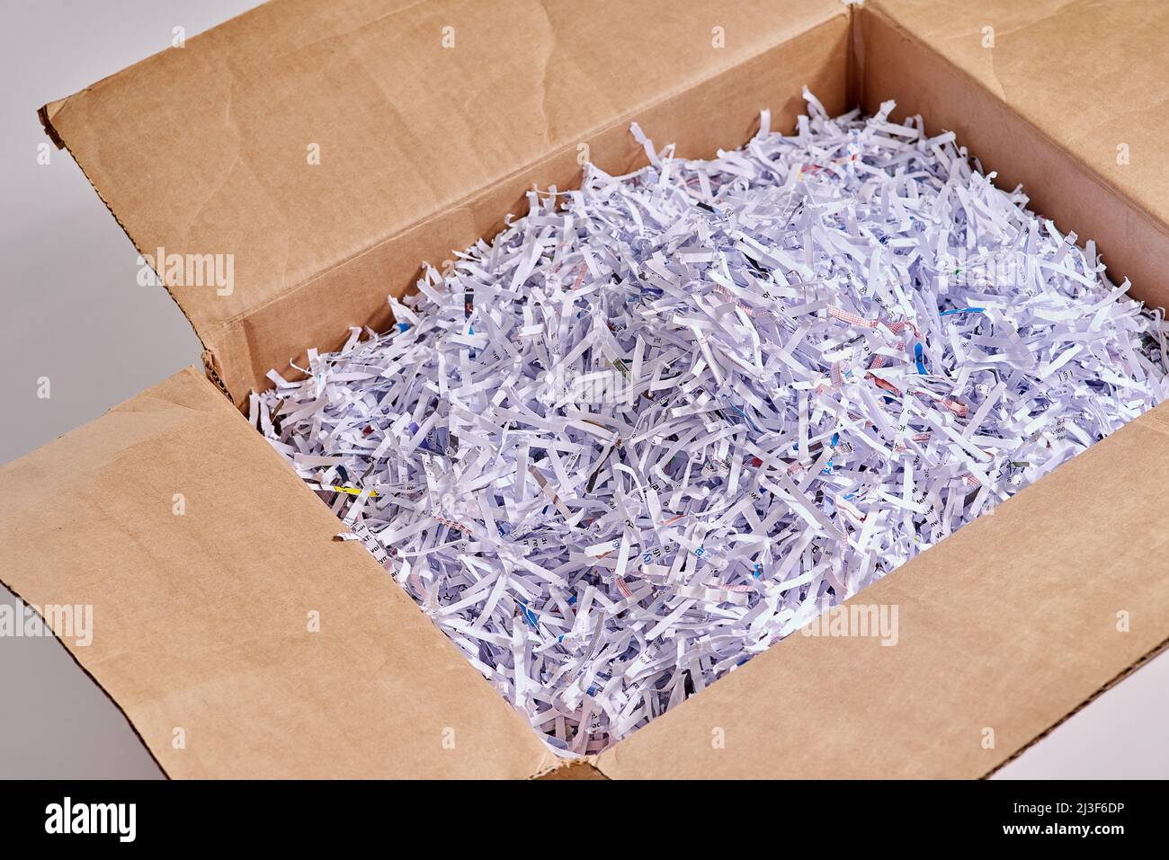 Le papier déchiqueté est idéal pour l'emballage. Studio photo de papier déchiqueté dans une boîte en carton sur fond gris. Banque D'Images