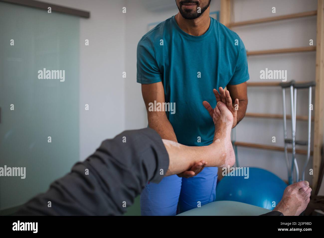 Gros plan d'un physiothérapeute s'exerçant avec la jambe du patient âgé dans une salle de physiothérapie. Banque D'Images
