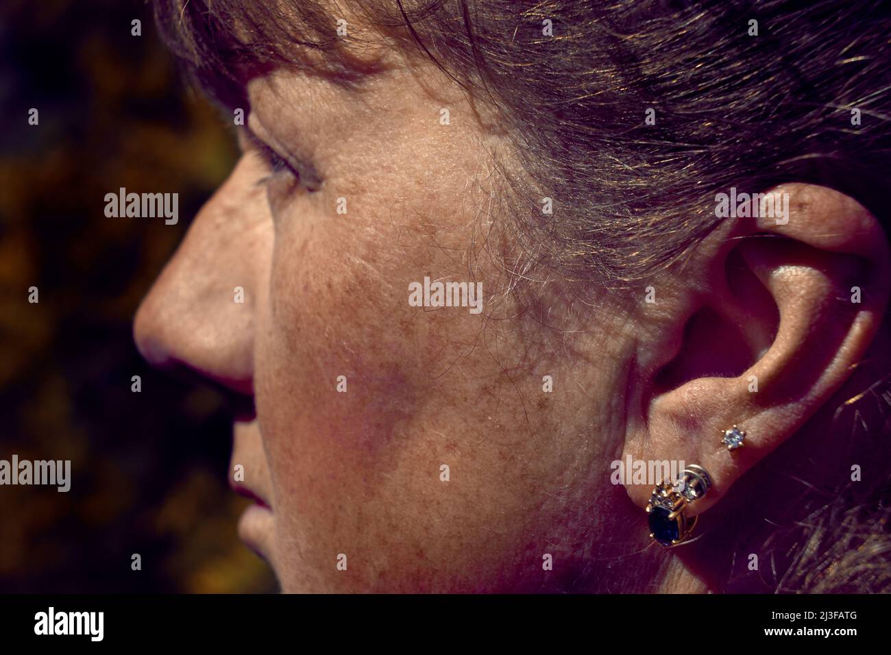 Portrait d'une femme adulte pensive avec boucles d'oreilles dans son oreille Banque D'Images