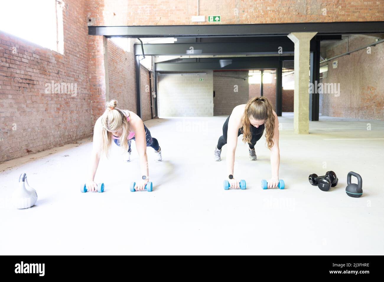 Deux jeunes femmes attirantes qui font des retouches à l'intérieur avec des cloches.Une femme de fitness s'entraîner dans une salle de sport polyvalente.Concept de fitness.Photo de haute qualité Banque D'Images