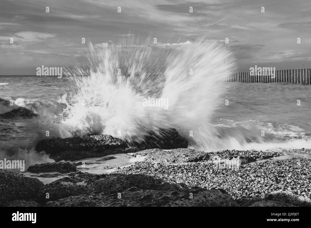 Les vagues se brisent au-dessus des rochers et provoquent des pulvérisations Banque D'Images