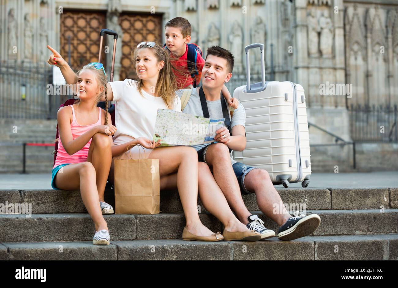 Famille de quatre personnes se détendant sur les marches de la vieille cathédrale et regardant la carte Banque D'Images