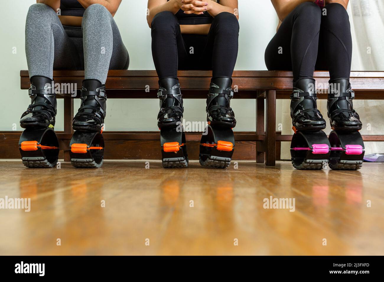 Au rez-de-chaussée des athlètes féminines en vêtements de sport et chaussures de saut assis sur le banc et se reposer pendant la pause dans l'entraînement de fitness dans la salle de gym Banque D'Images