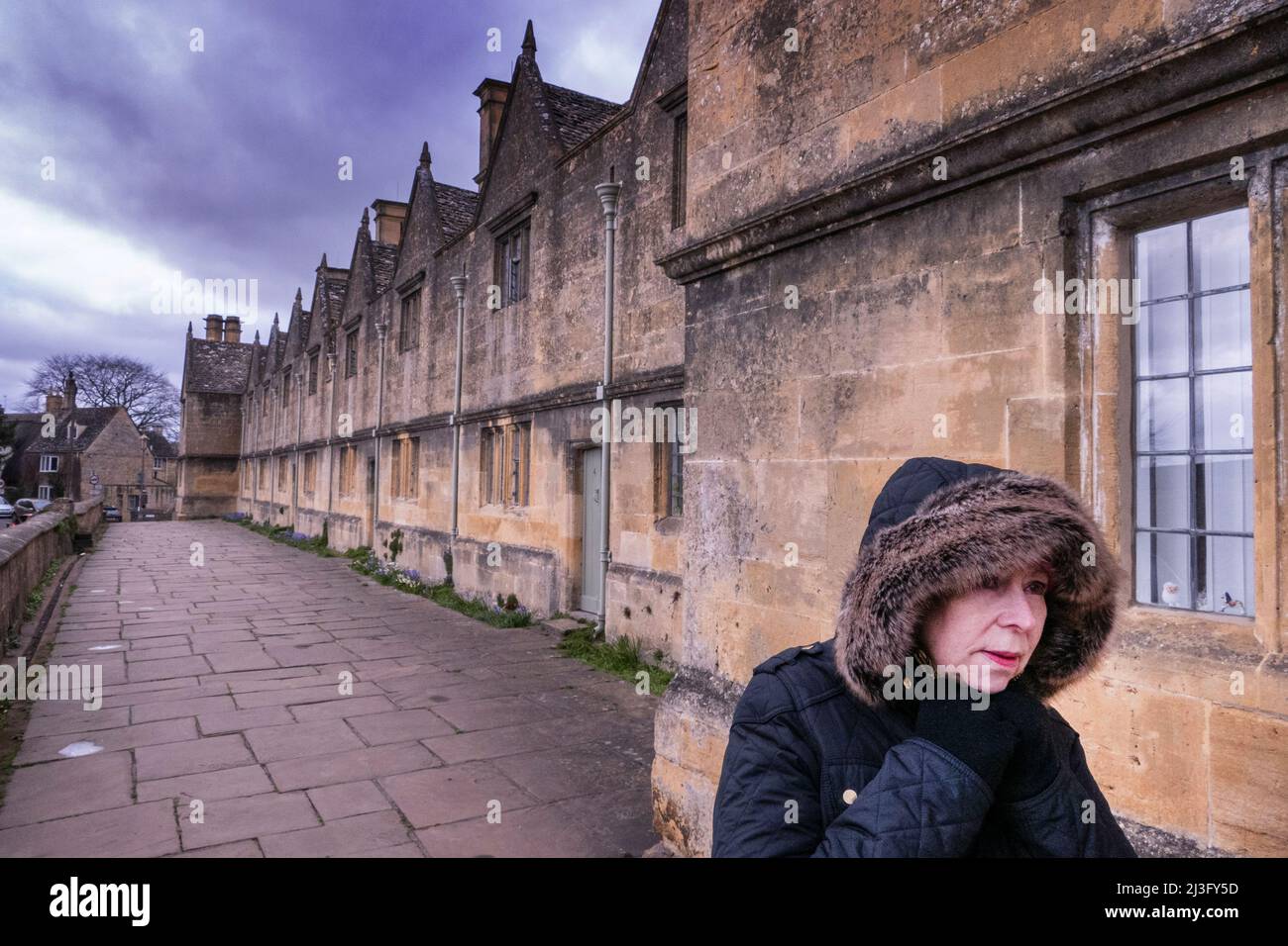 Femme passant devant une terrasse de chalets à Chipping Campden Royaume-Uni Banque D'Images