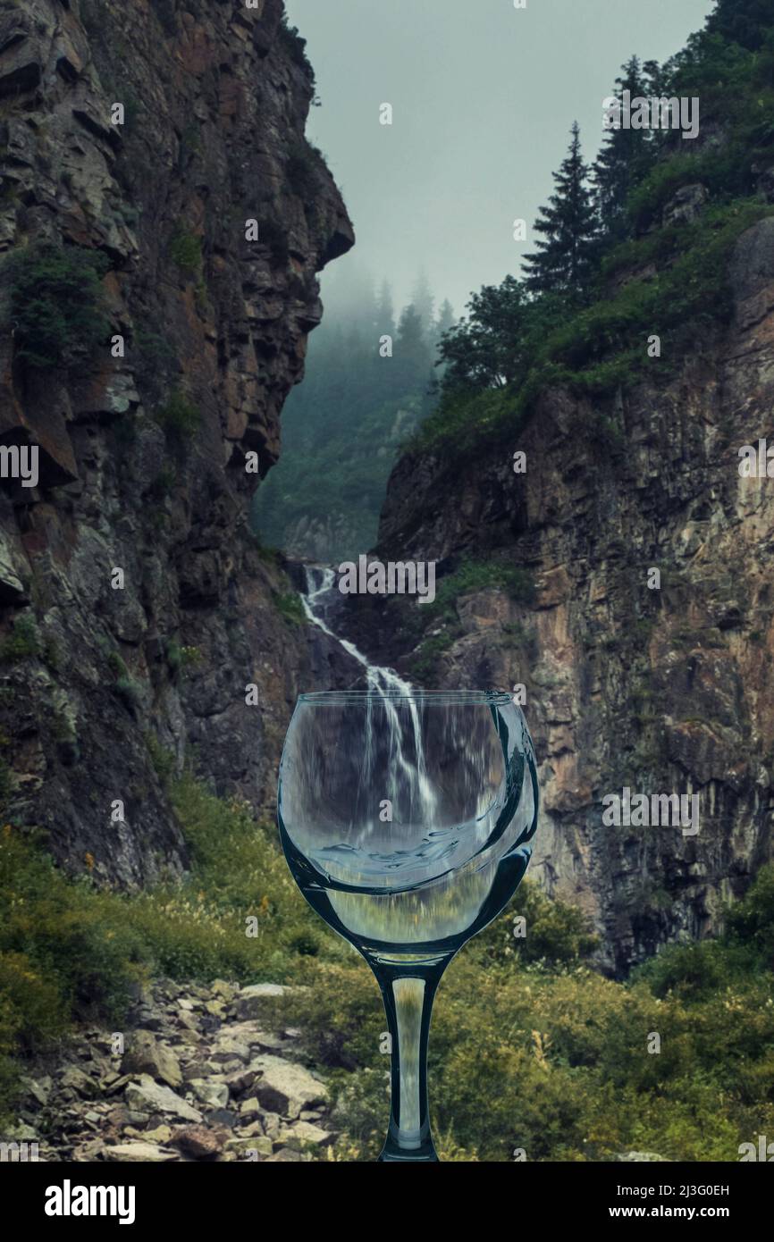 un verre transparent avec de l'eau propre et des éclaboussures sur le fond de la cascade de montagne Banque D'Images