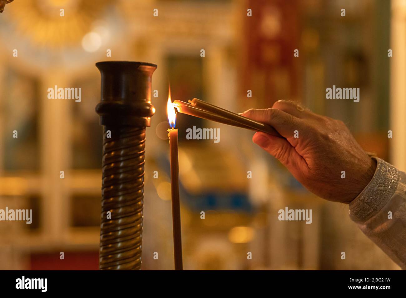 Église orthodoxe. Christianisme. Main de prêtre éclairant des bougies allumées dans l'église orthodoxe traditionnelle à la veille de Pâques ou à Noël. Religion foi prier symbole Banque D'Images