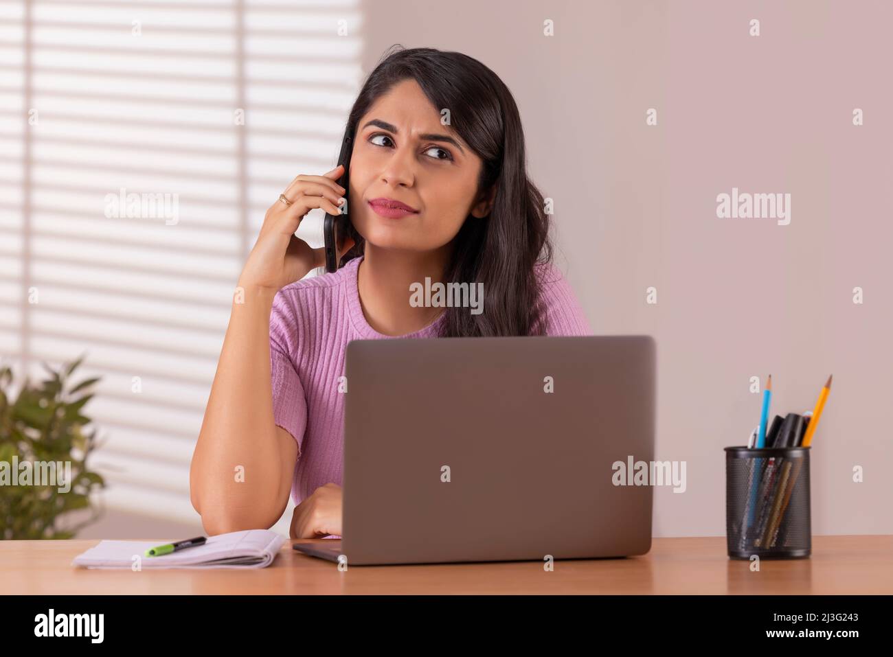 Portrait d'une jeune femme de direction parlant sur un smartphone tout en travaillant au bureau Banque D'Images