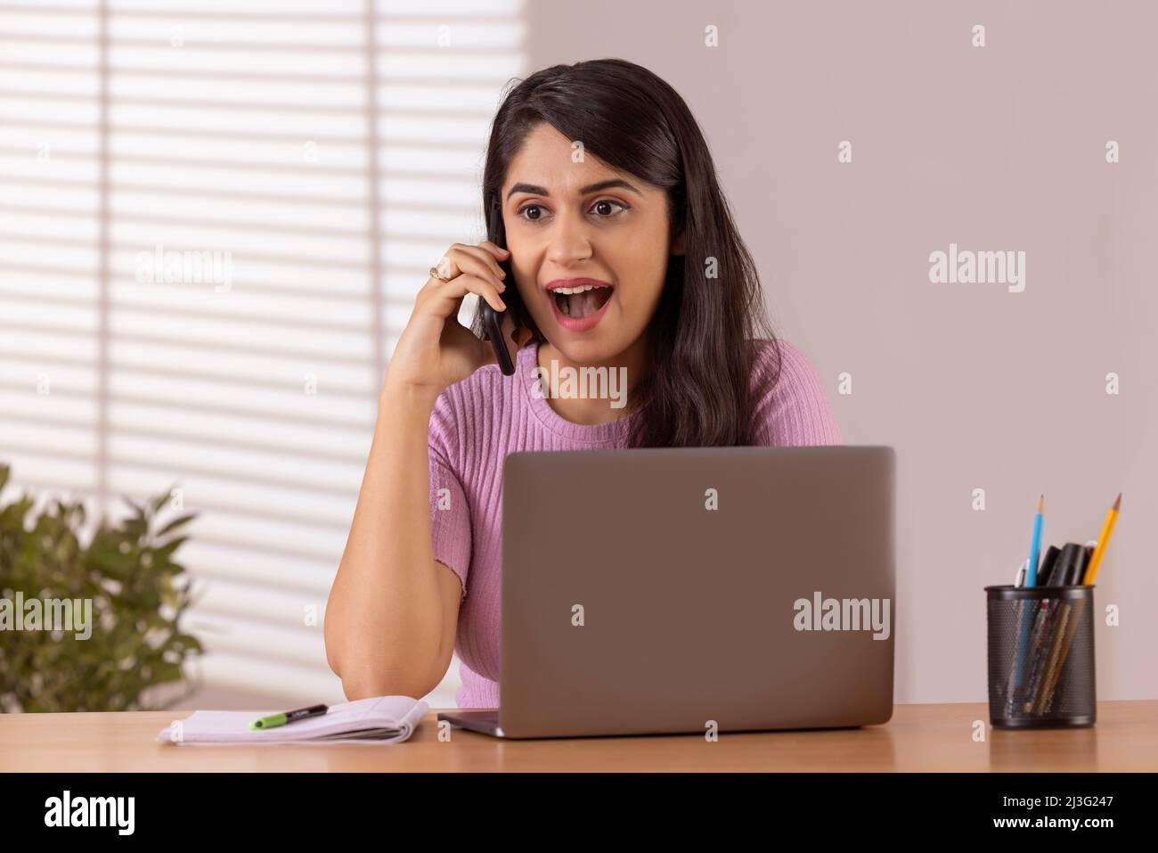 Portrait d'une jeune femme de direction parlant sur un smartphone tout en travaillant au bureau Banque D'Images